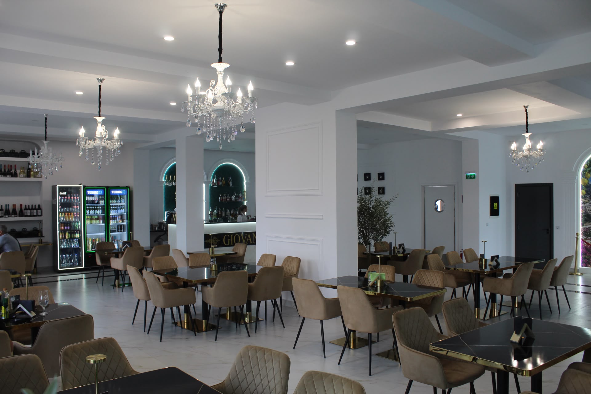 Sala principală de mese la Giovanni's, cu ferestre arcuite, candelabre de cristal, podele de marmură și portrete contemporane în tonuri închise